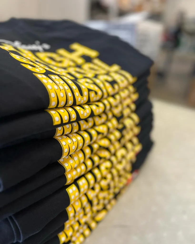 Folded stack of black t-shirts with yellow printing